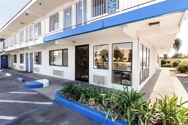 Hotel features a flat roof and ground-floor windows, surrounded by a garden and parking area.