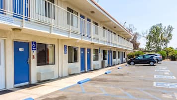 Un motel con varias habitaciones, cada una con una puerta azul y un letrero de estacionamiento para discapacitados.