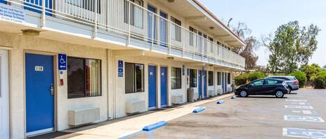 Un motel con varias habitaciones, cada una con una puerta azul y un letrero de estacionamiento para discapacitados.