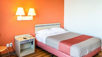 Una habitación de hotel con cama, mesita de noche, lámpara y una silla.