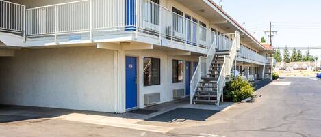 Un motel con una estructura de dos pisos, un área exterior cubierta y un estacionamiento.