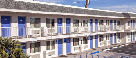 Un motel con varias habitaciones, cada una con una puerta azul y un balcón.