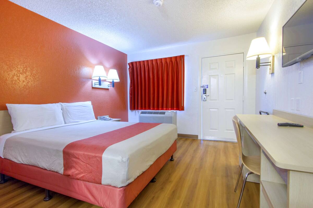 A hotel room with a bed, a desk, and a chair.