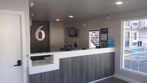 Un comptoir d’accueil avec une plaque portant le numéro « 6 », un ordinateur et un panneau d’accueil encadré.