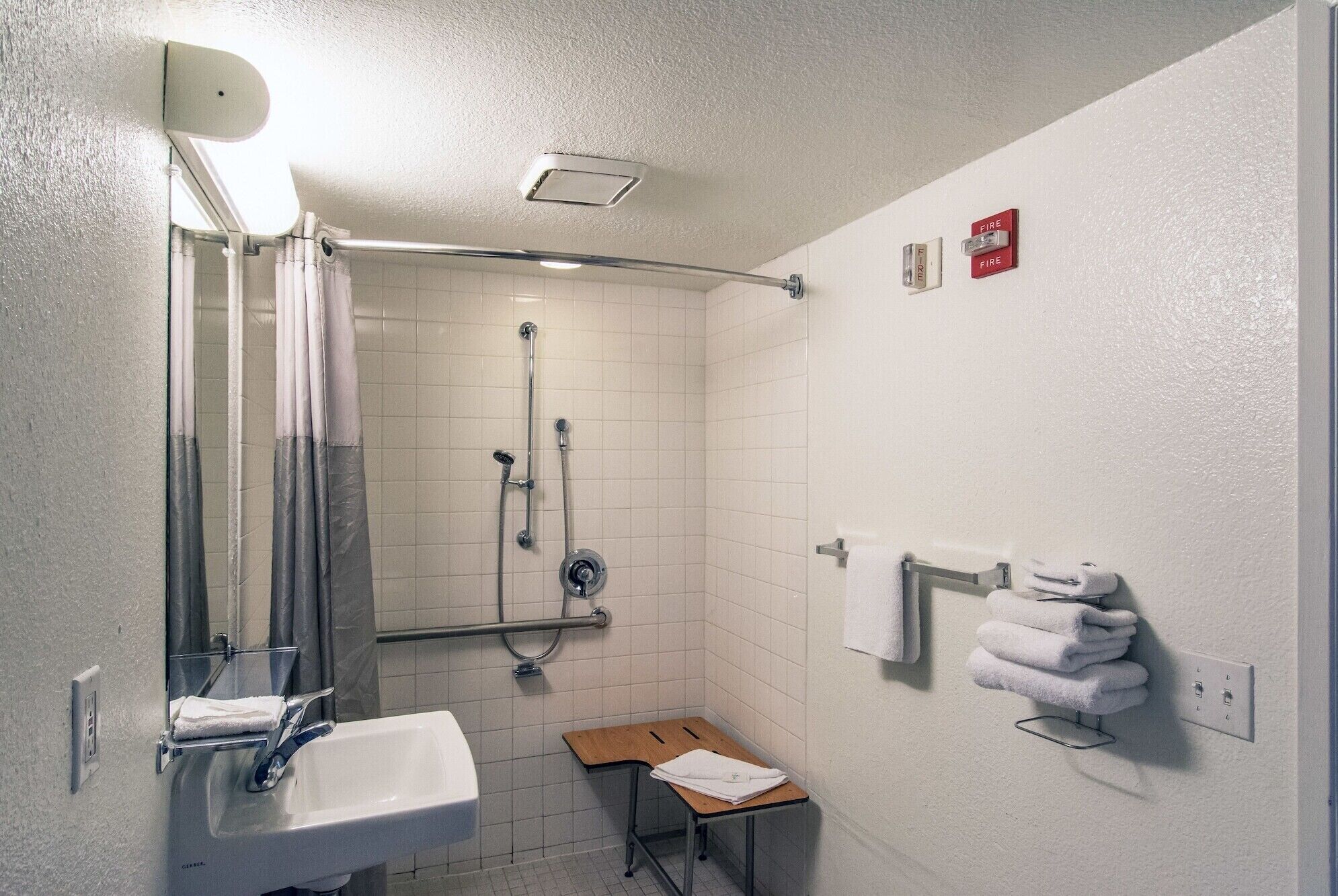 A small, clean bathroom with a shower, a sink, and a towel rack.
