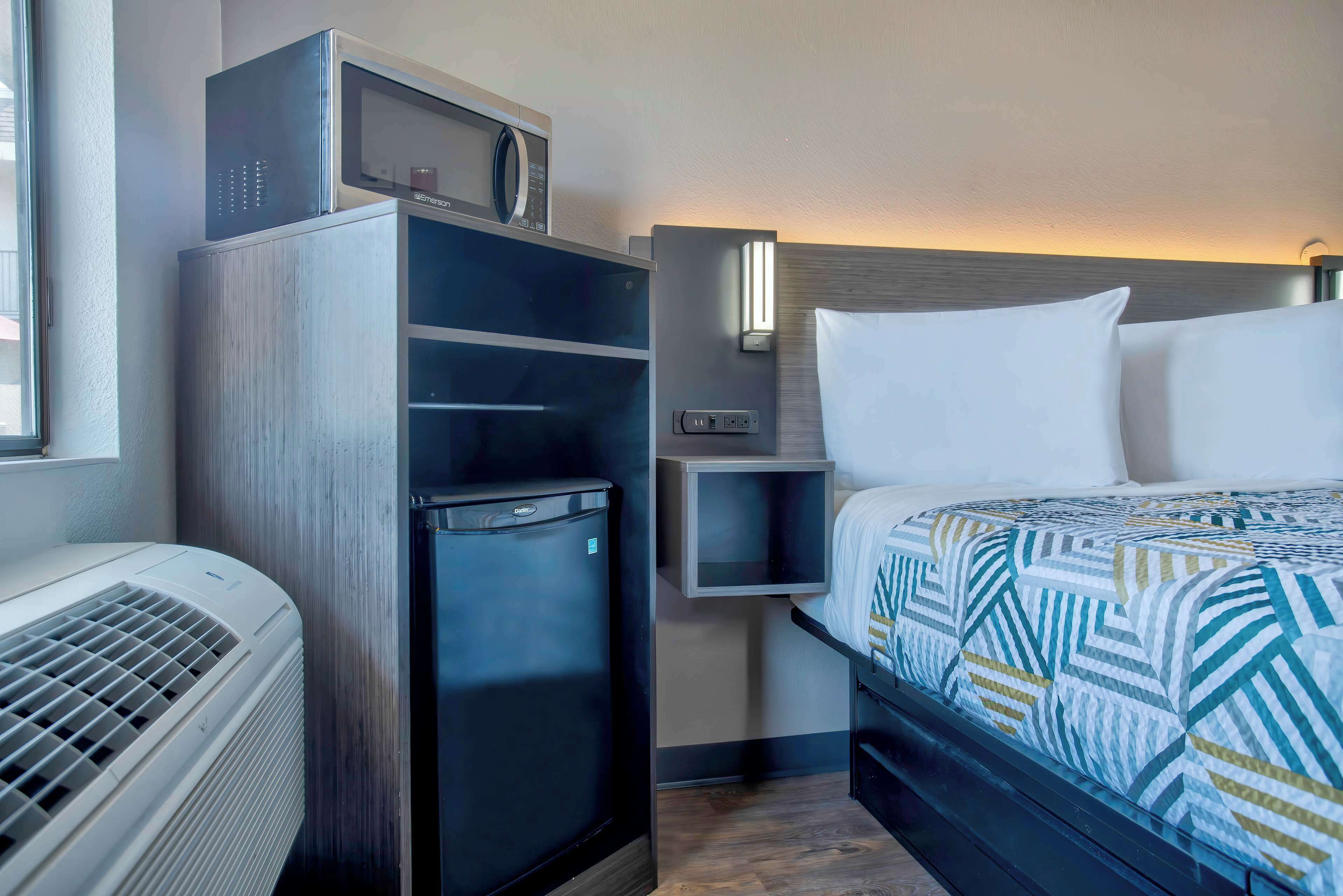 Une chambre d’hôtel équipée d’un lit, d’un petit réfrigérateur, d’un four à micro-ondes et d’un radiateur.