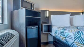 Une chambre d’hôtel équipée d’un lit, d’un petit réfrigérateur, d’un four à micro-ondes et d’un radiateur.