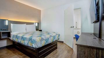 A bedroom with a bed, bedside table, and a TV mounted on the wall.