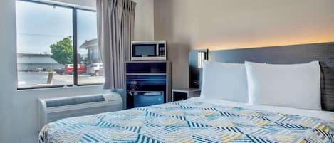 Une chambre d’hôtel équipée d’un lit, d’un four à micro-ondes, d’une télévision et offrant une vue sur la rue.