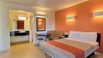Una habitación de hotel con cama, escritorio, silla y baño.