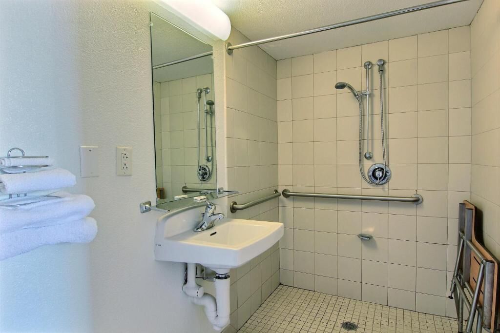 Un baño con lavamanos, espejo y ducha.