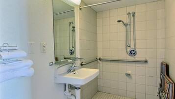 Un baño con lavamanos, espejo y ducha.