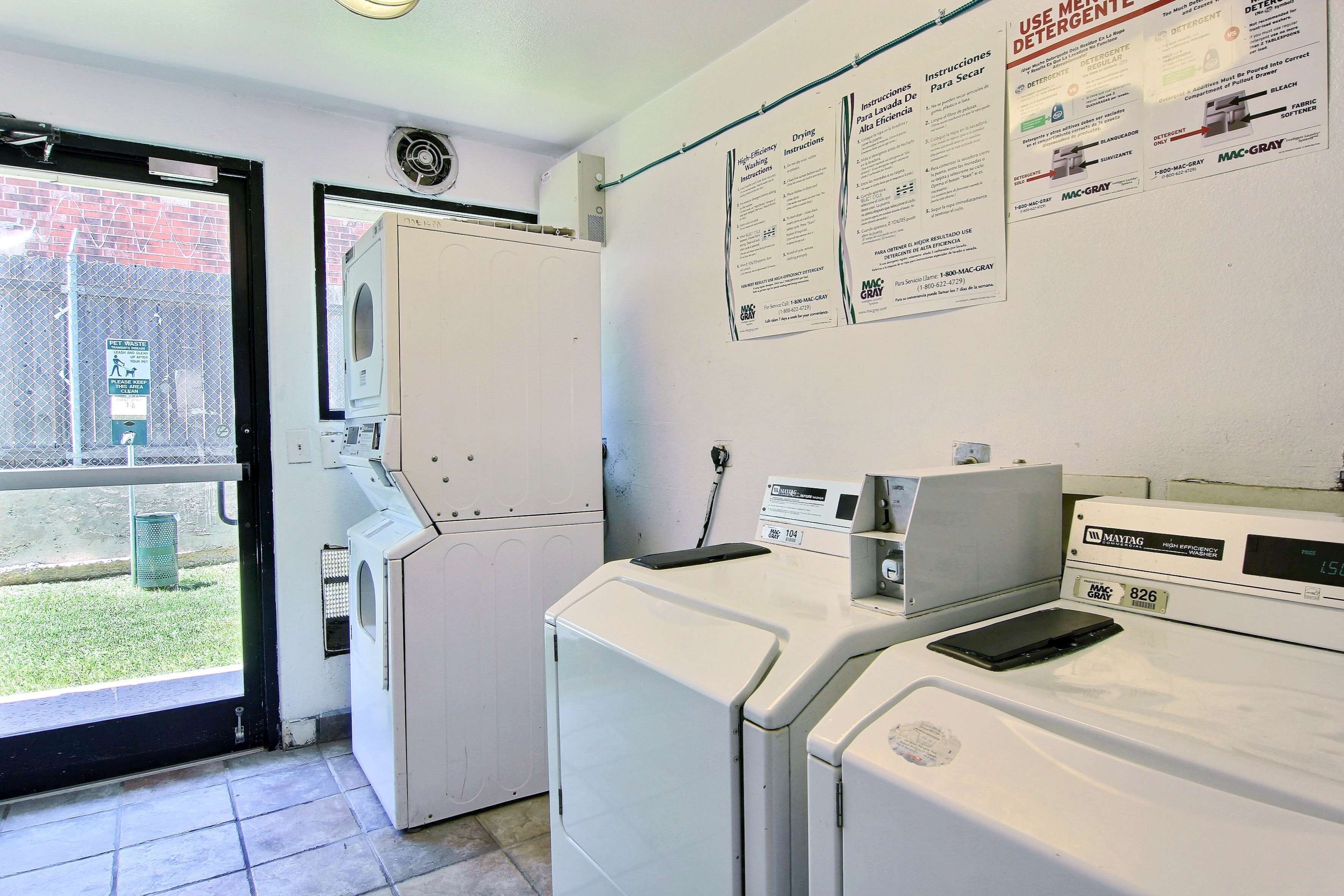 A laundry room with a washing machine, dryer, and a window with a view of a grassy area.