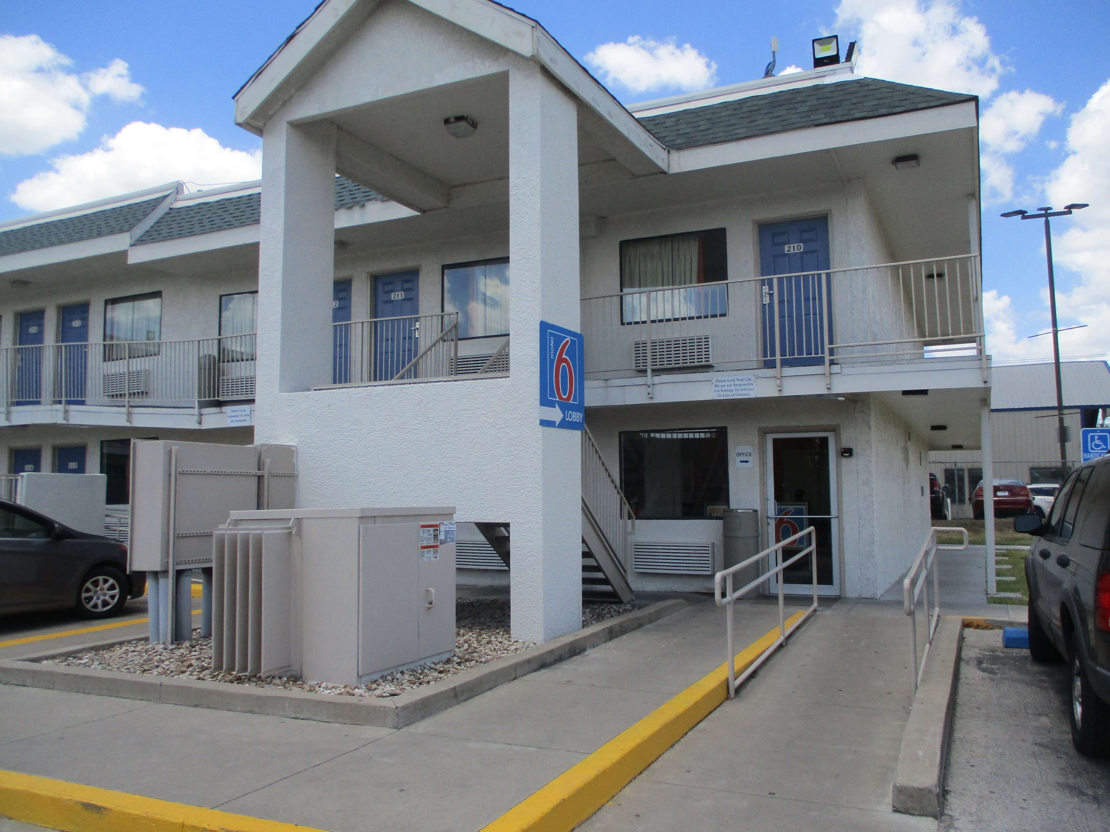 Un motel de varios pisos con una recepción central y un área de estacionamiento.