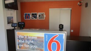 A motel reception desk with a large sign reading "We'll leave the light on for you." - Motel 6 Austin, TX - North Central (Austin)