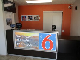 A motel reception desk with a large sign reading "We'll leave the light on for you."
