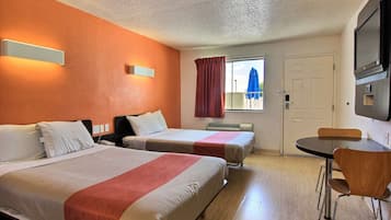 A hotel room with two beds, a dining table, and a TV.