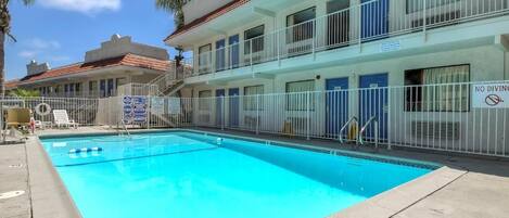 A hotel with a swimming pool, multiple balconies, and a no diving sign.