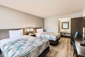 A hotel room with two beds, a desk, and a chair.