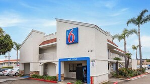 A 6 Motel with a 'Welcome' sign, a 'Tow Away' sign, and a number '6117' on the building.