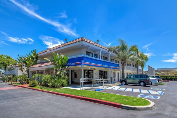 A building with a blue and white facade, a covered entrance, and a parking lot with handicapped parking spaces. - Motel 6 Pomona, CA - Los Angeles (Pomona)