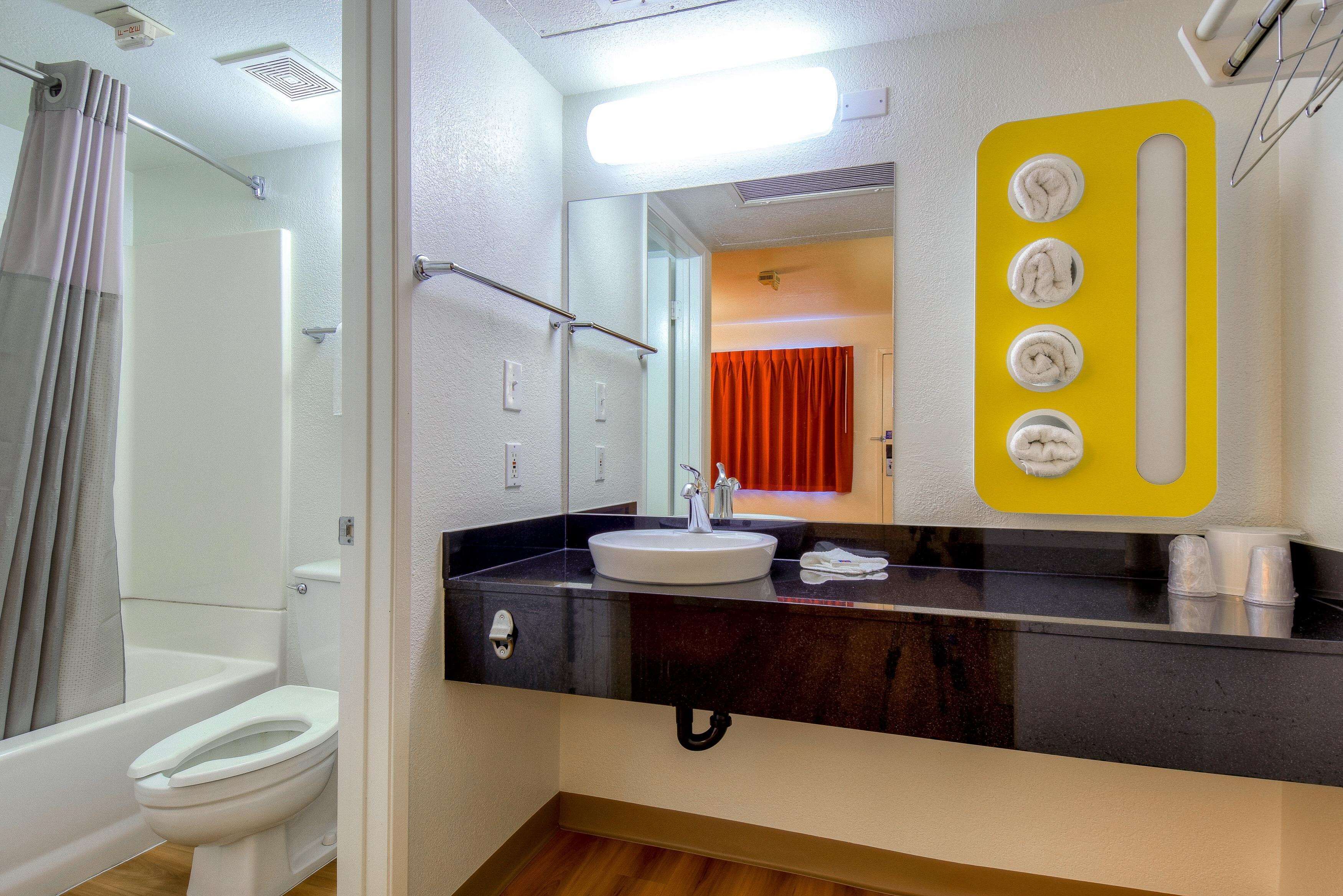 A bathroom with a white toilet, a black sink, a mirror with a yellow frame, and a shower curtain.