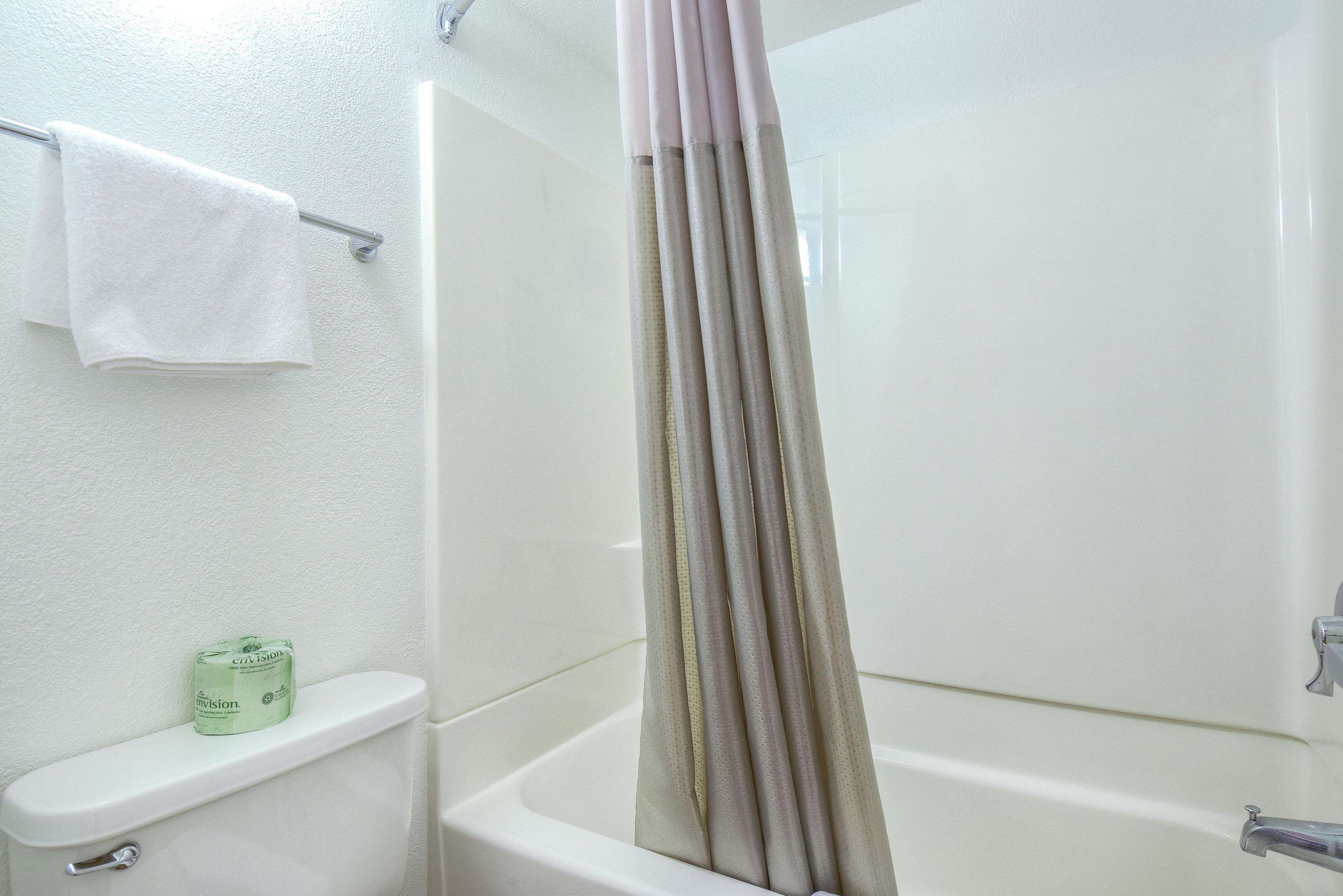 A bathroom with a toilet, a towel rack with a white towel, and a shower curtain.