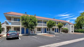 Un motel con techo de tejas rojas, varios balcones y un estacionamiento.