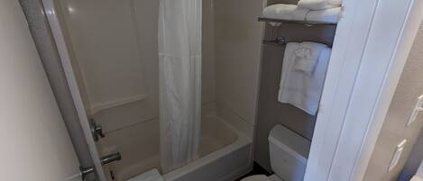 A bathroom with a shower, toilet, and a towel rack.