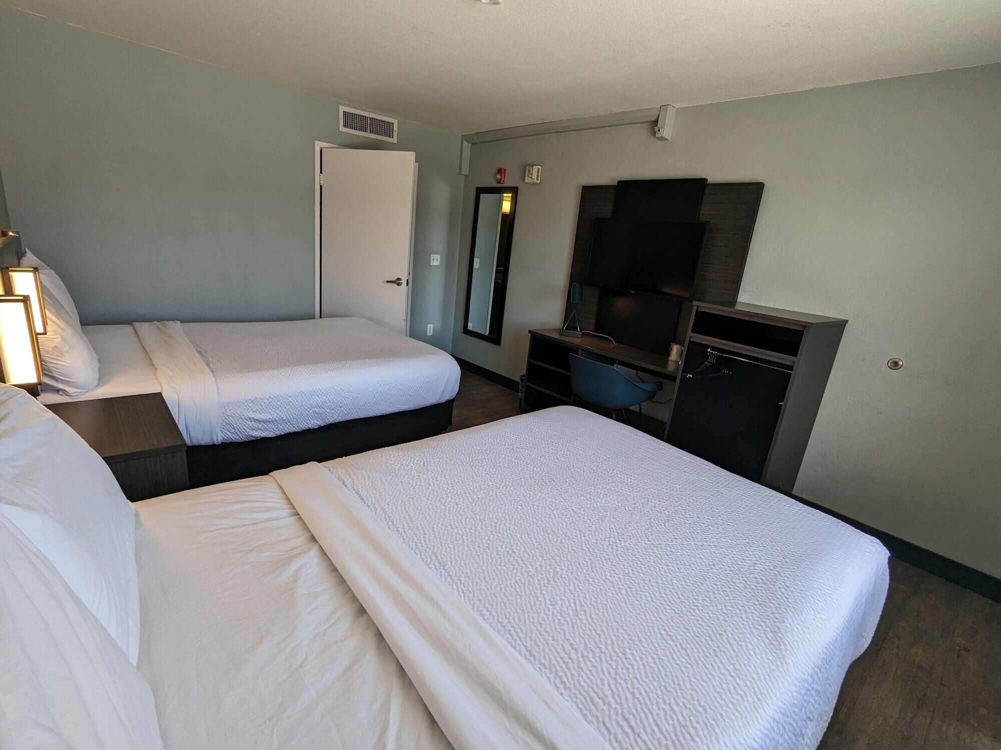 Une chambre d’hôtel avec deux lits, un bureau, une télévision et une armoire.