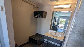 Un baño con lavamanos, espejo y un pequeño estante sobre el espejo.