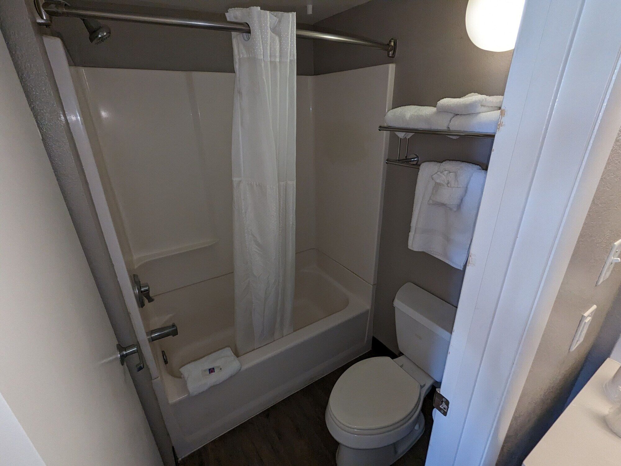 Une petite salle de bain avec une douche, des toilettes et un porte-serviettes.