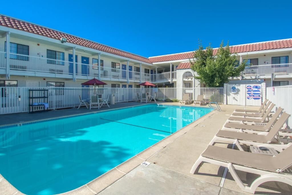 Ein Hotel mit Schwimmbad, Liegestühlen und einer umzäunten Terrassenanlage.