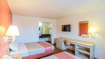 Habitación de hotel con dos camas, un escritorio, una silla, un televisor y un espejo.