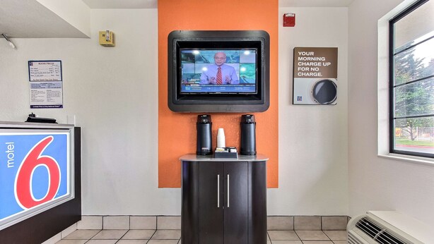 A motel interior with a television mounted on a wall, a coffee machine, and a sign indicating morning charge for no charge. - Motel 6 Salinas, CA - North Monterey Area (Salinas)