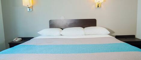 A hotel room with a bed, two bedside lamps, a phone, and a nightstand.