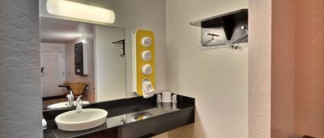 A modern bathroom with a large mirror, a sink, and a towel rack.
