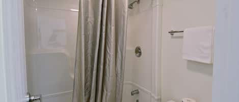 A bathroom with a shower, toilet, and towel rack.