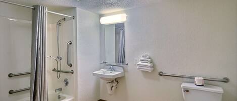 A bathroom with a shower, sink, toilet, and a mirror.
