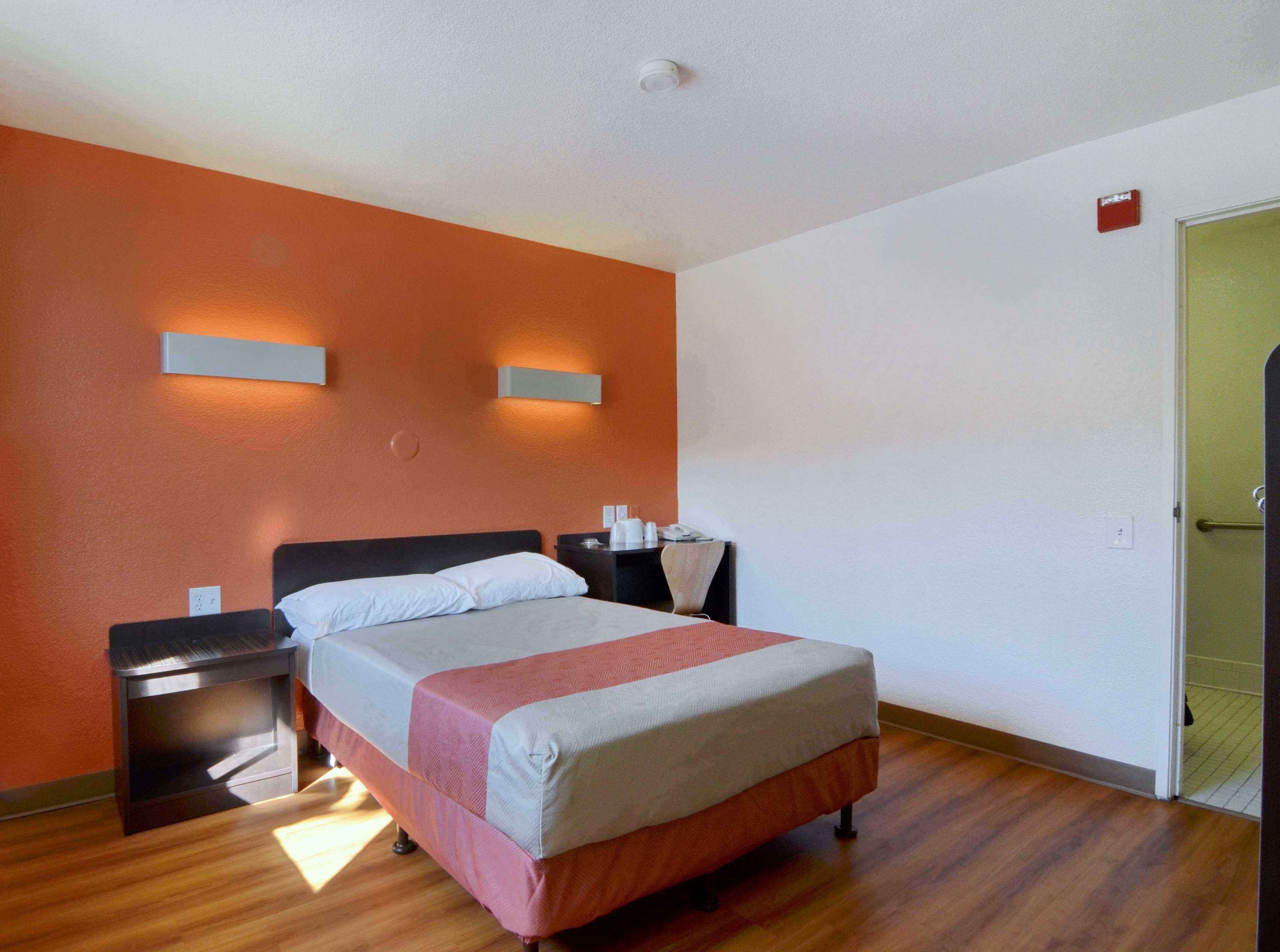 A hotel room with a bed, nightstands, and a door.