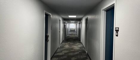 Un largo pasillo de hotel, estrecho, con pisos alfombrados y puertas a ambos lados.