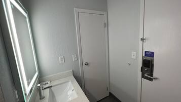 Une salle de bain équipée d’un lavabo, d’un miroir et d’une porte dotée d’une serrure de sécurité.
