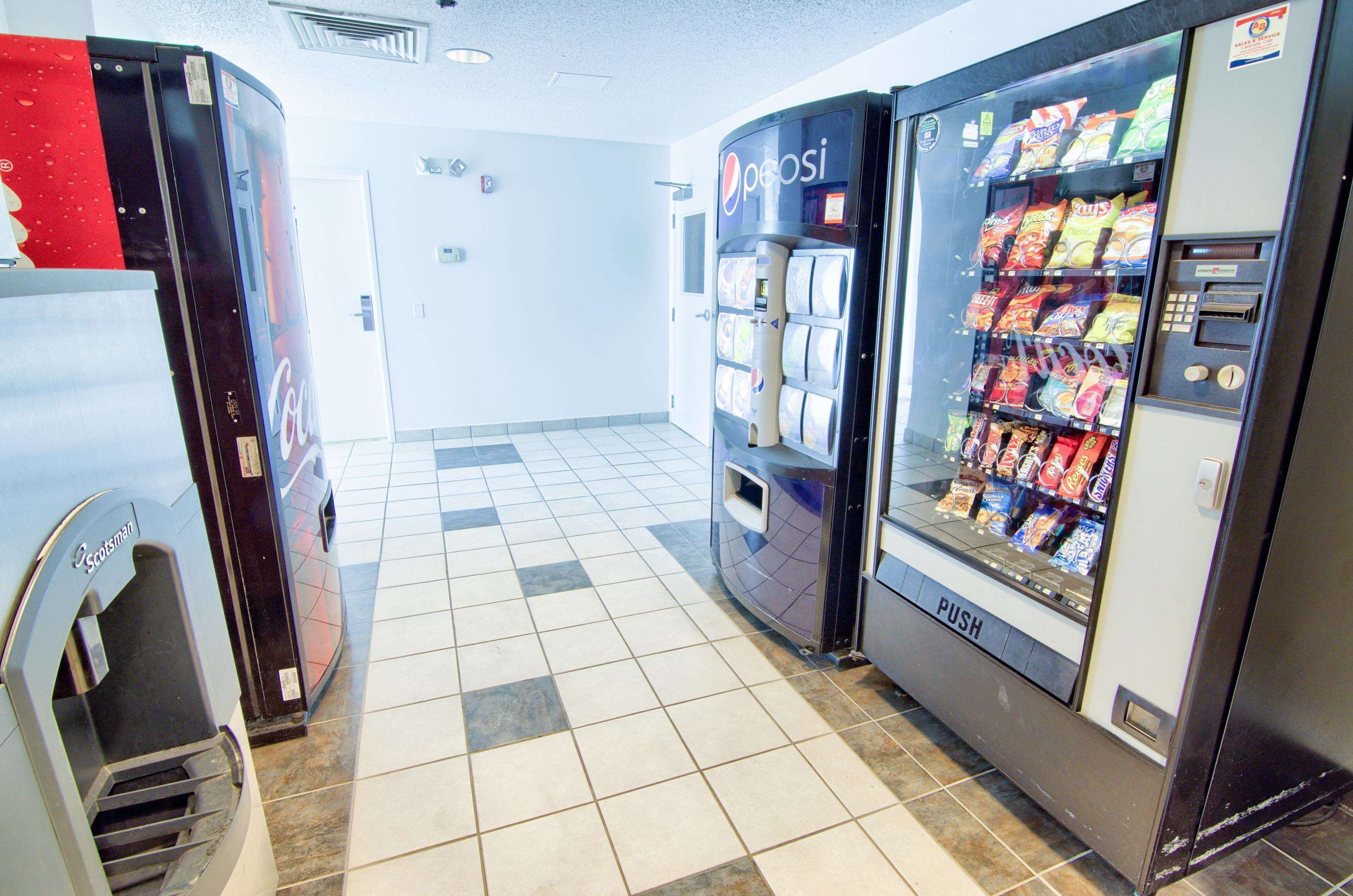 Un espace dédié aux distributeurs automatiques, avec un distributeur de Pepsi et un autre distributeur où l’on peut appuyer sur un bouton pour obtenir un produit.