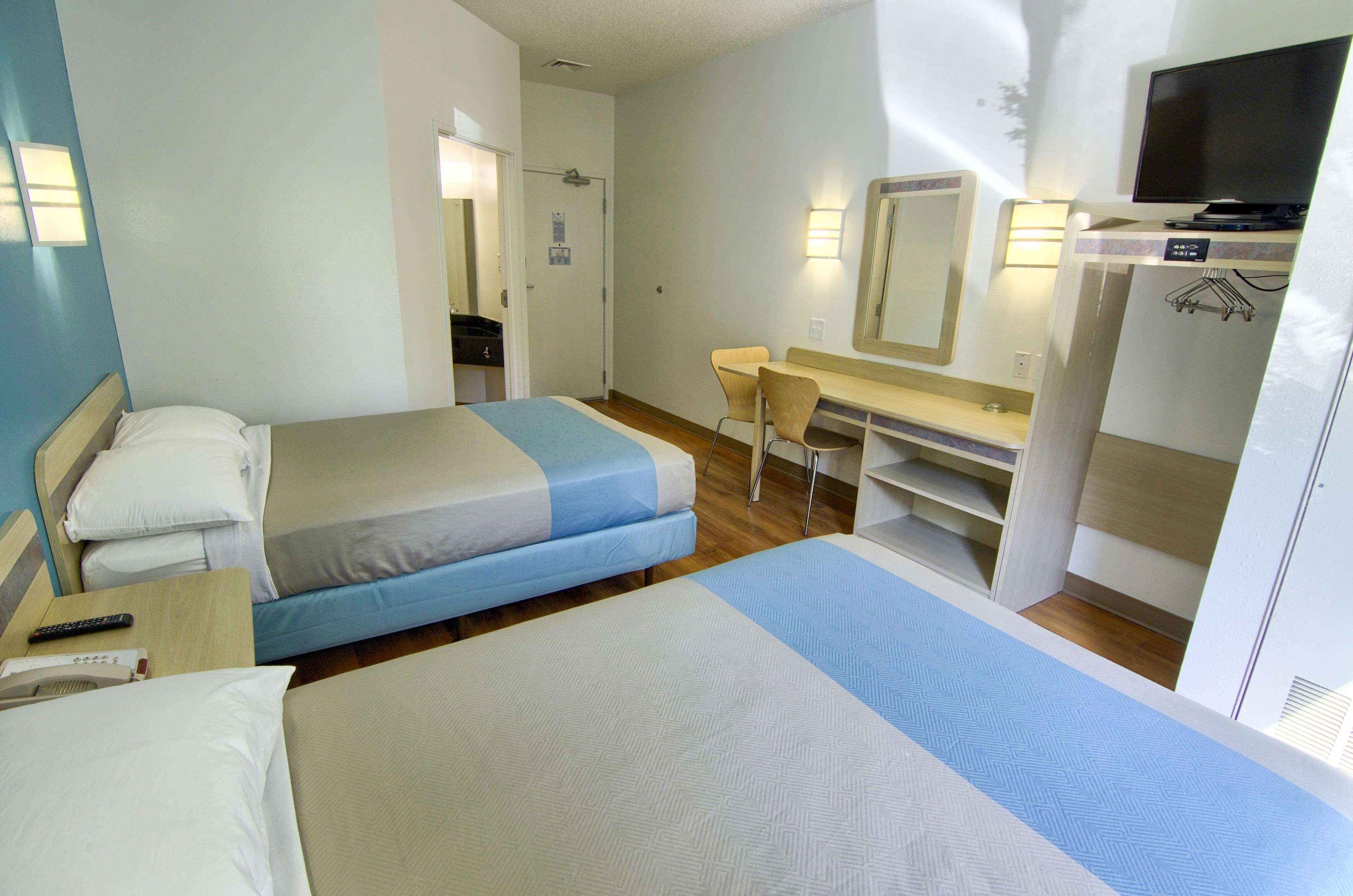 A hotel room with two beds, a desk, a chair, a TV, and a wardrobe.