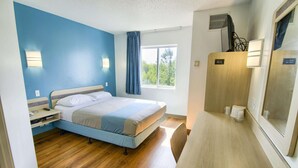 A bedroom with a bed, bedside table, and a window with curtains.
