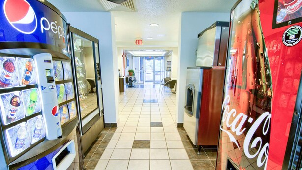A hallway with vending machines, including Pepsi and Coca-Cola, and an exit sign.