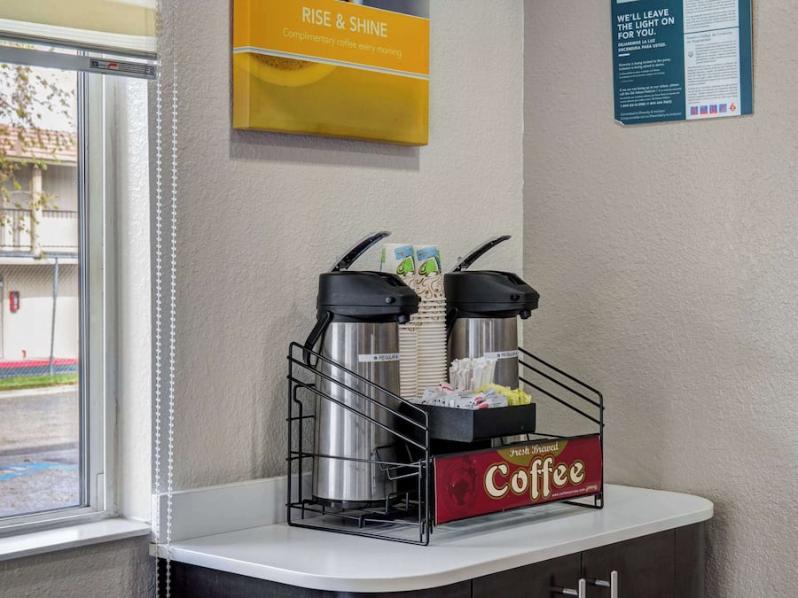 Een koffiehoek met twee koffiezetapparaten en een doos koffiecups op een aanrecht.