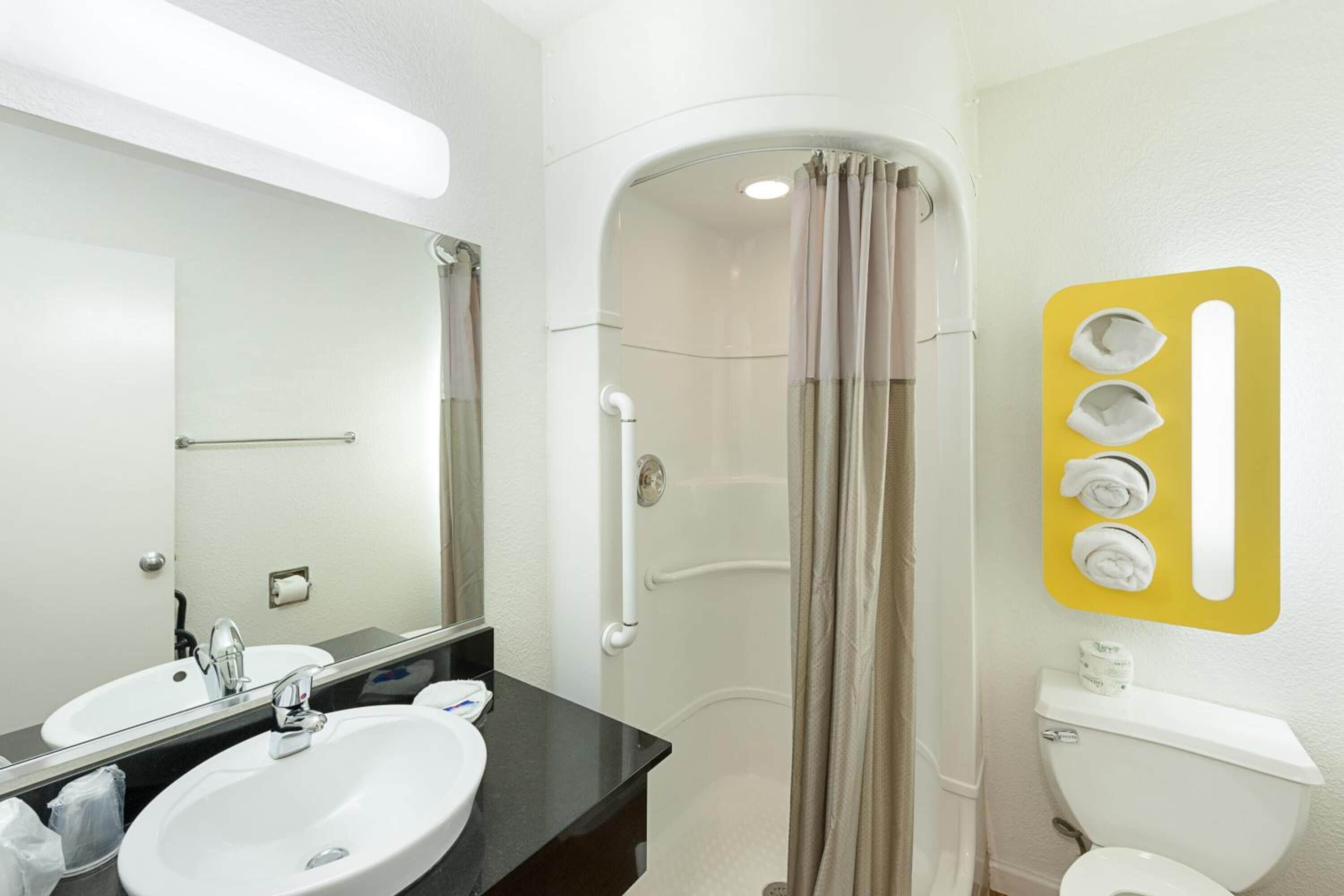 Un bagno con lavandino bianco, uno specchio, cabina doccia e un water.