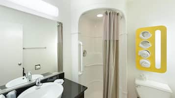Un bagno con lavandino bianco, uno specchio, cabina doccia e un water.