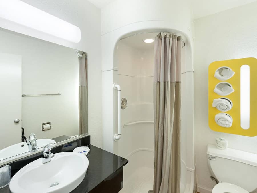Un bagno con lavandino bianco, uno specchio, cabina doccia e un water.